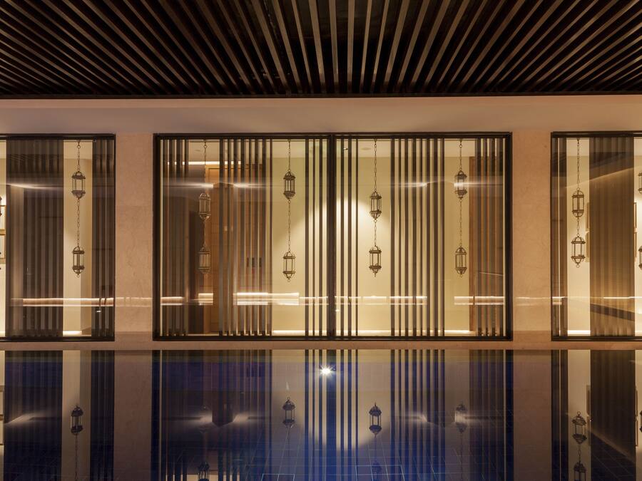 A modern interior with a reflective floor, vertical blinds, and hanging lanterns.