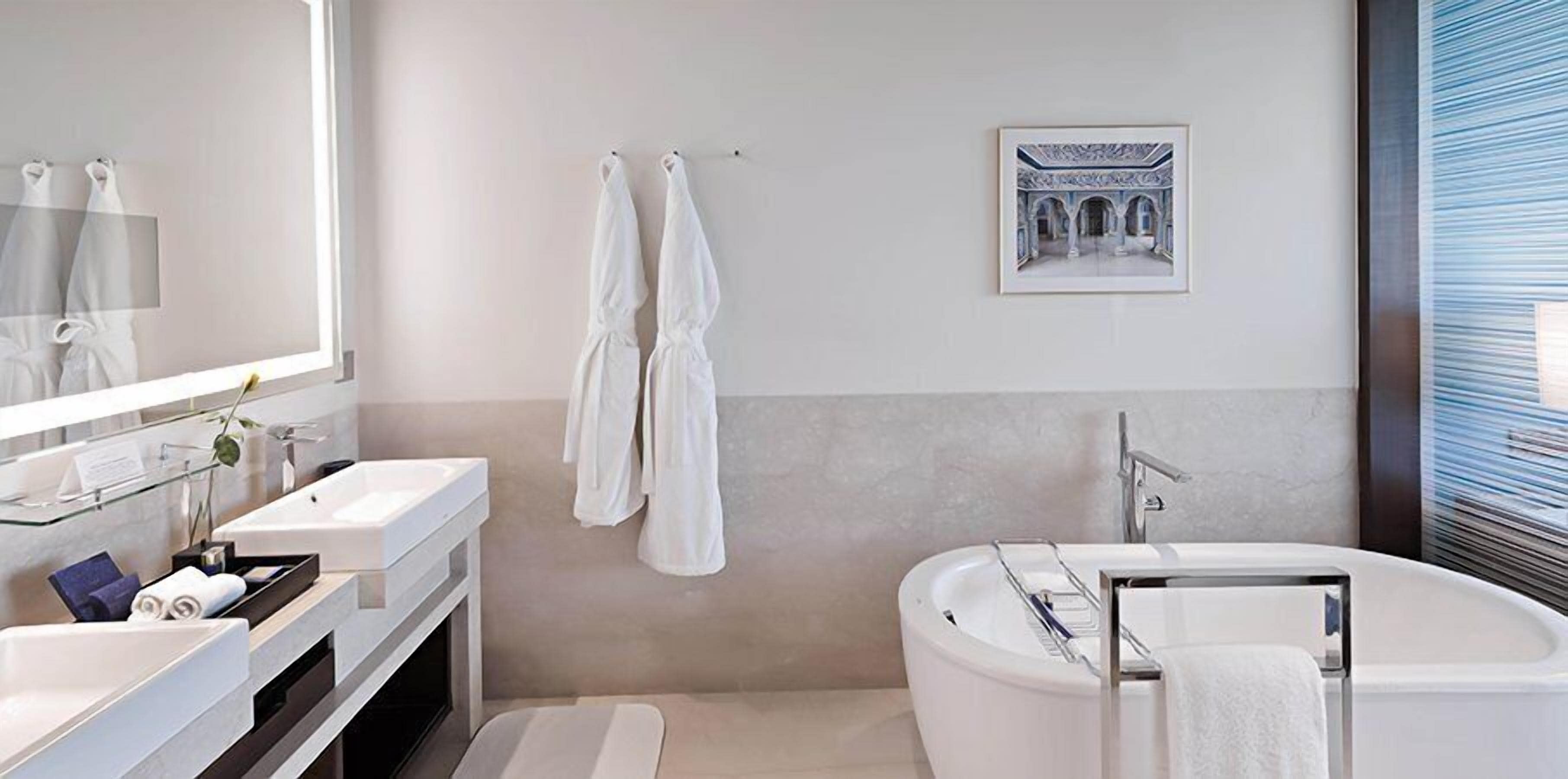 A modern bathroom with a large bathtub, a double sink vanity, and a large mirror.