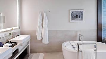 A modern bathroom with a large bathtub, a double sink vanity, and a large mirror.