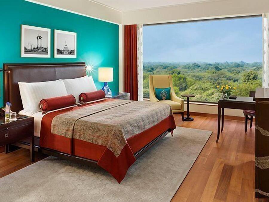 A hotel room with a large bed, a desk, and a view of the outdoors.