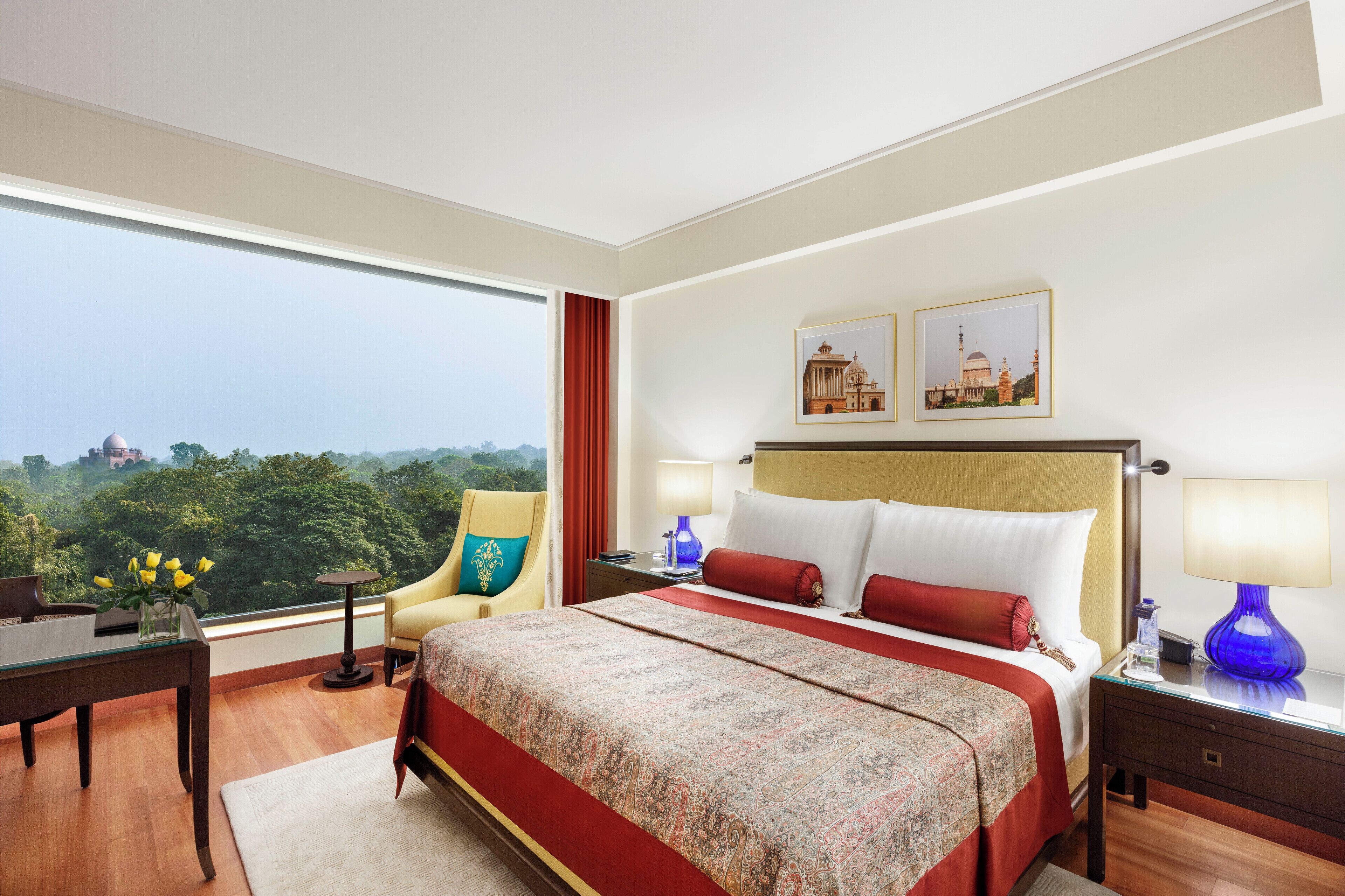 Habitación de hotel con una cama grande, un escritorio, una silla y vistas de la ciudad.
