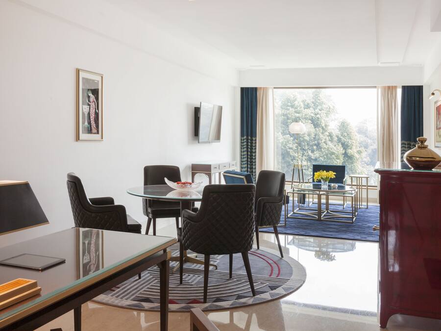 Un comedor moderno con una mesa de vidrio, sillas negras y un armario rojo.