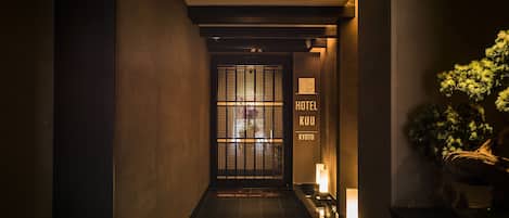 A hallway with a traditional Japanese gate, a sign reading "KUU HOTEL KYOTO," and a potted plant on the right.