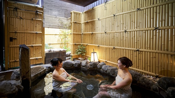 A traditional Japanese onsen with stone walls and bamboo screens. - Hotel Kuu Kyoto (Kyoto)