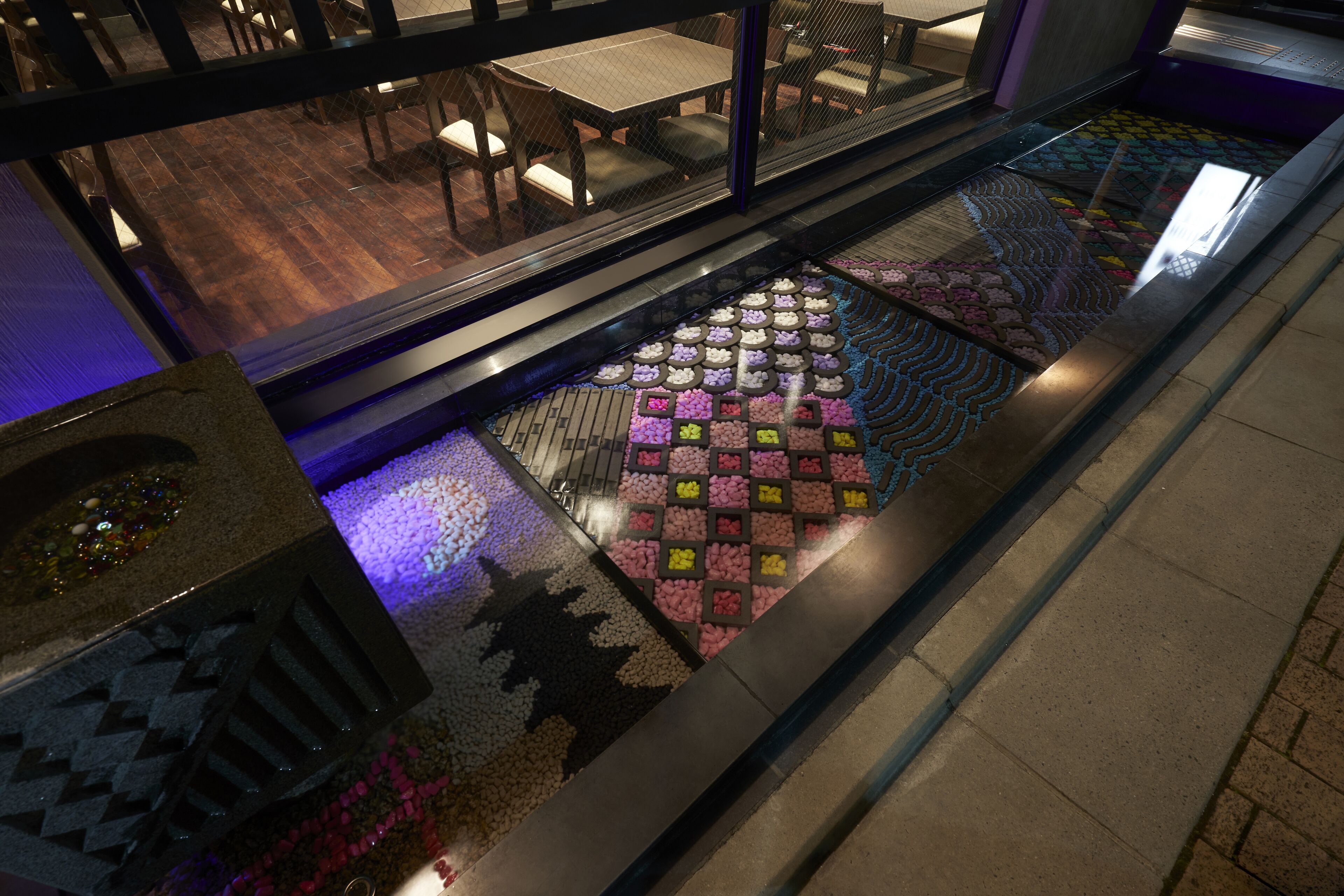 A hotel lobby with a glass railing, a patterned floor, and a view of the dining area.