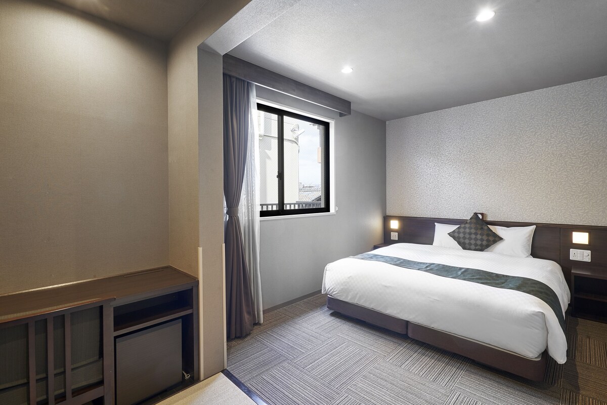 Habitación de hotel con una cama grande, un escritorio y un ventanal con cortinas.