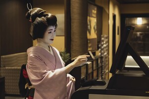 Una persona vestida con traje tradicional sentada en un escritorio con una computadora.