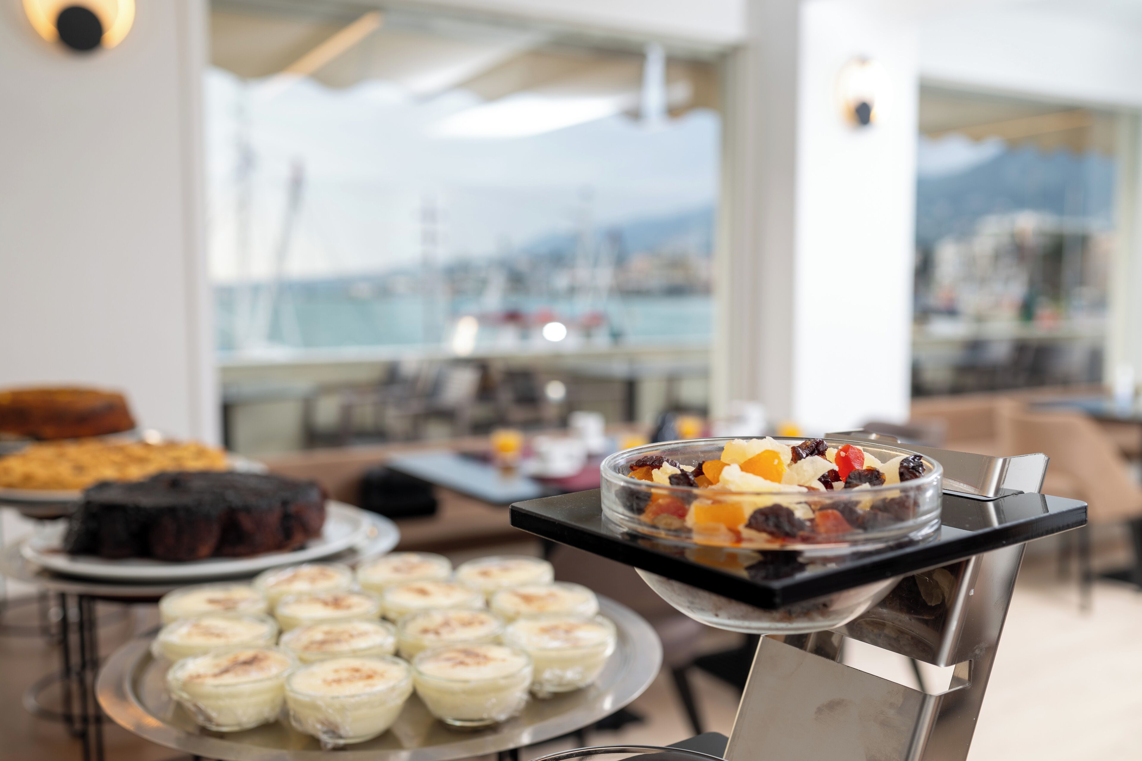 En buffet med forskellige retter, udsigt over bybilledet gennem store vinduer og et moderne interiør.