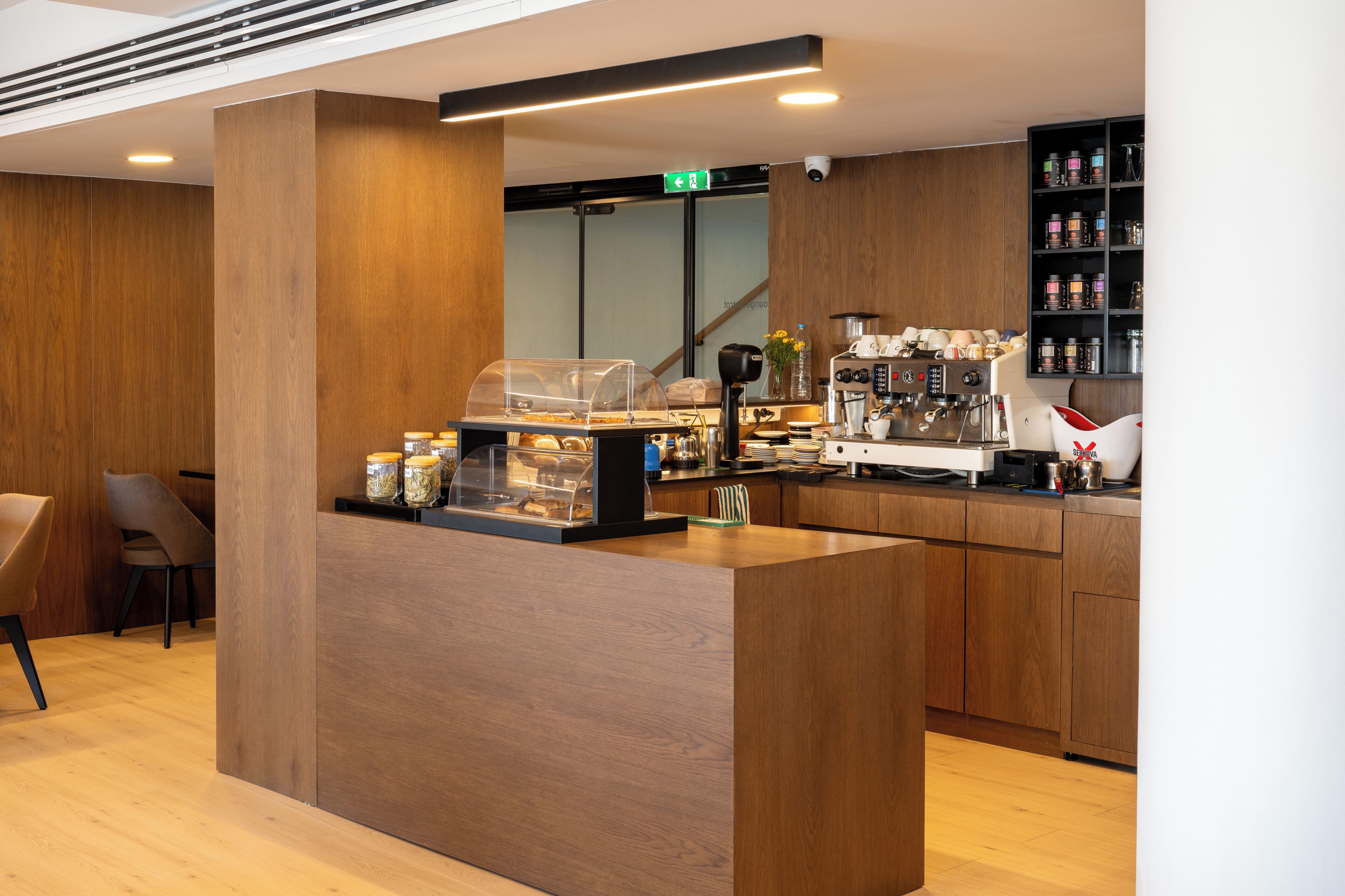A modern coffee shop interior with a wooden counter, seating area, and a variety of coffee-making equipment.