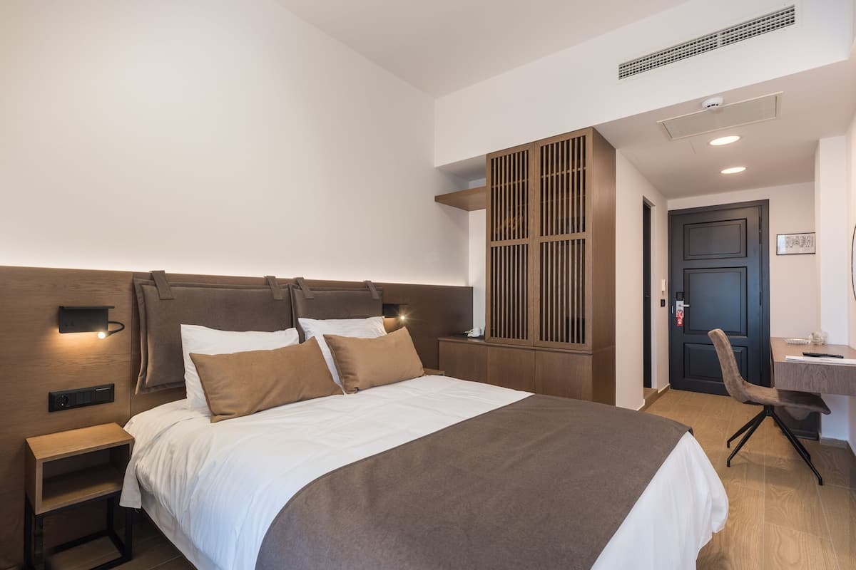 A hotel room with a large bed, a desk, and a chair.