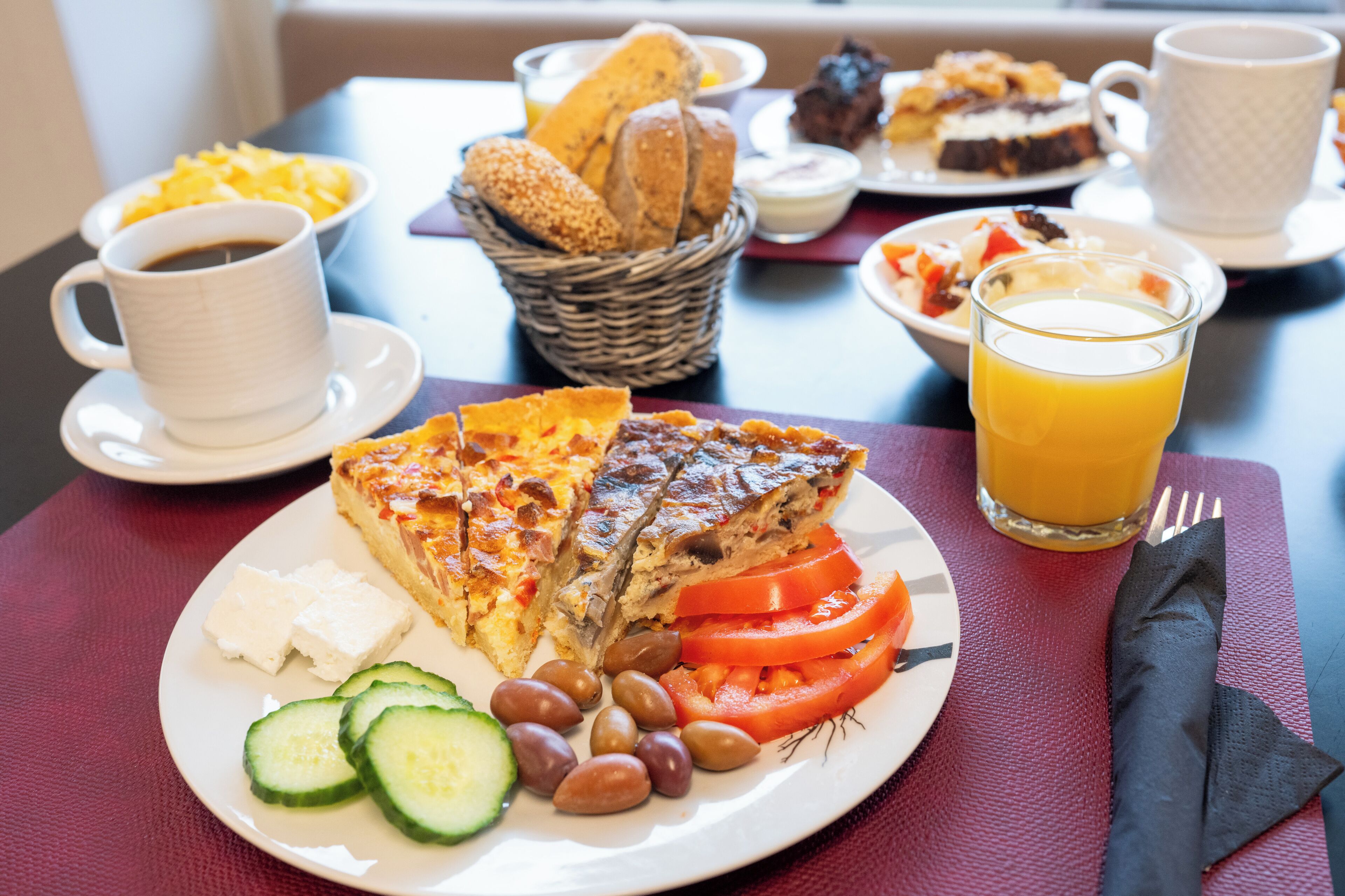 A breakfast setting with a plate of food, a cup of coffee, and a glass of orange juice.