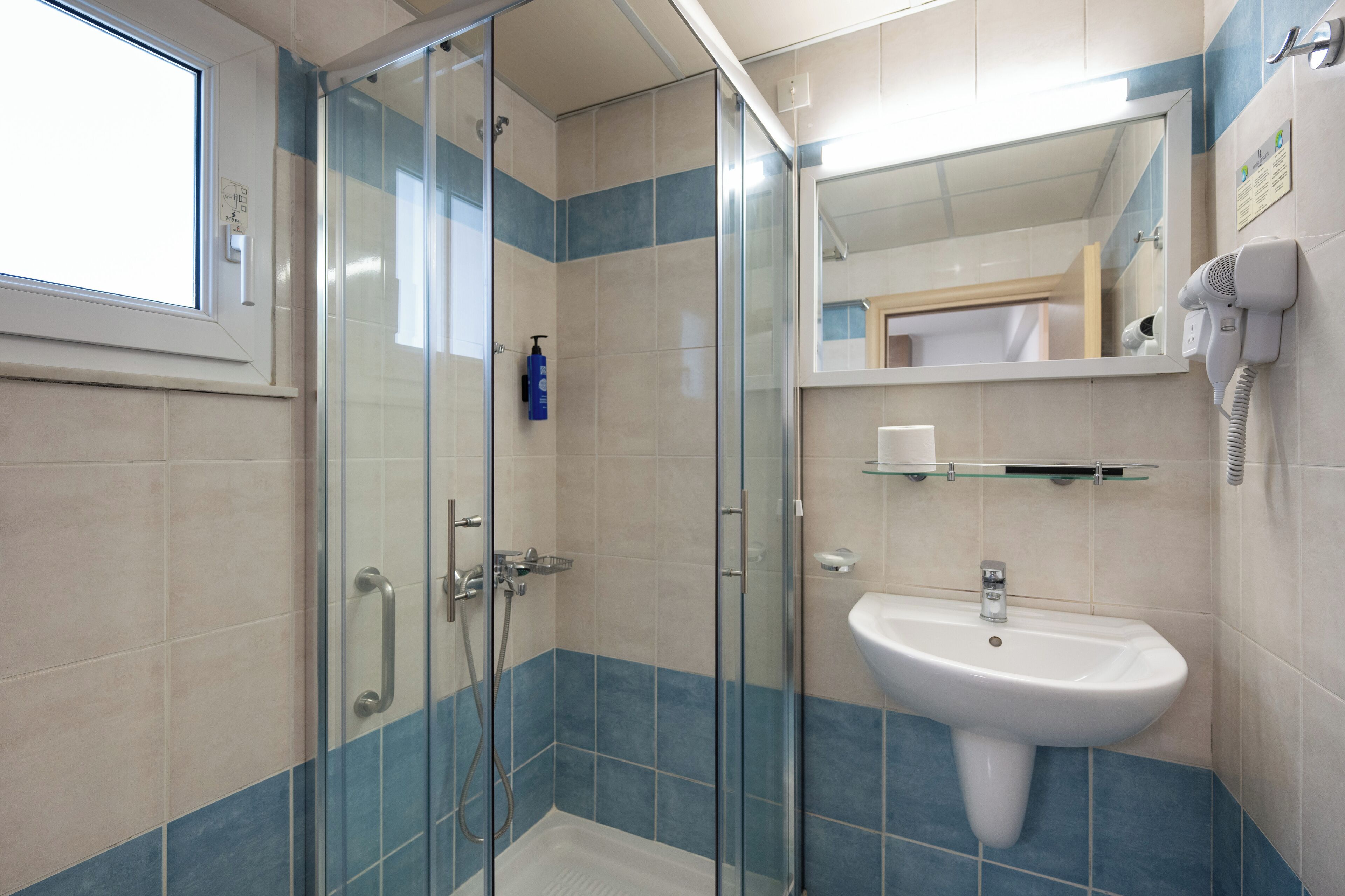 Une salle de bain moderne avec une douche à parois de verre, un lavabo et un miroir.