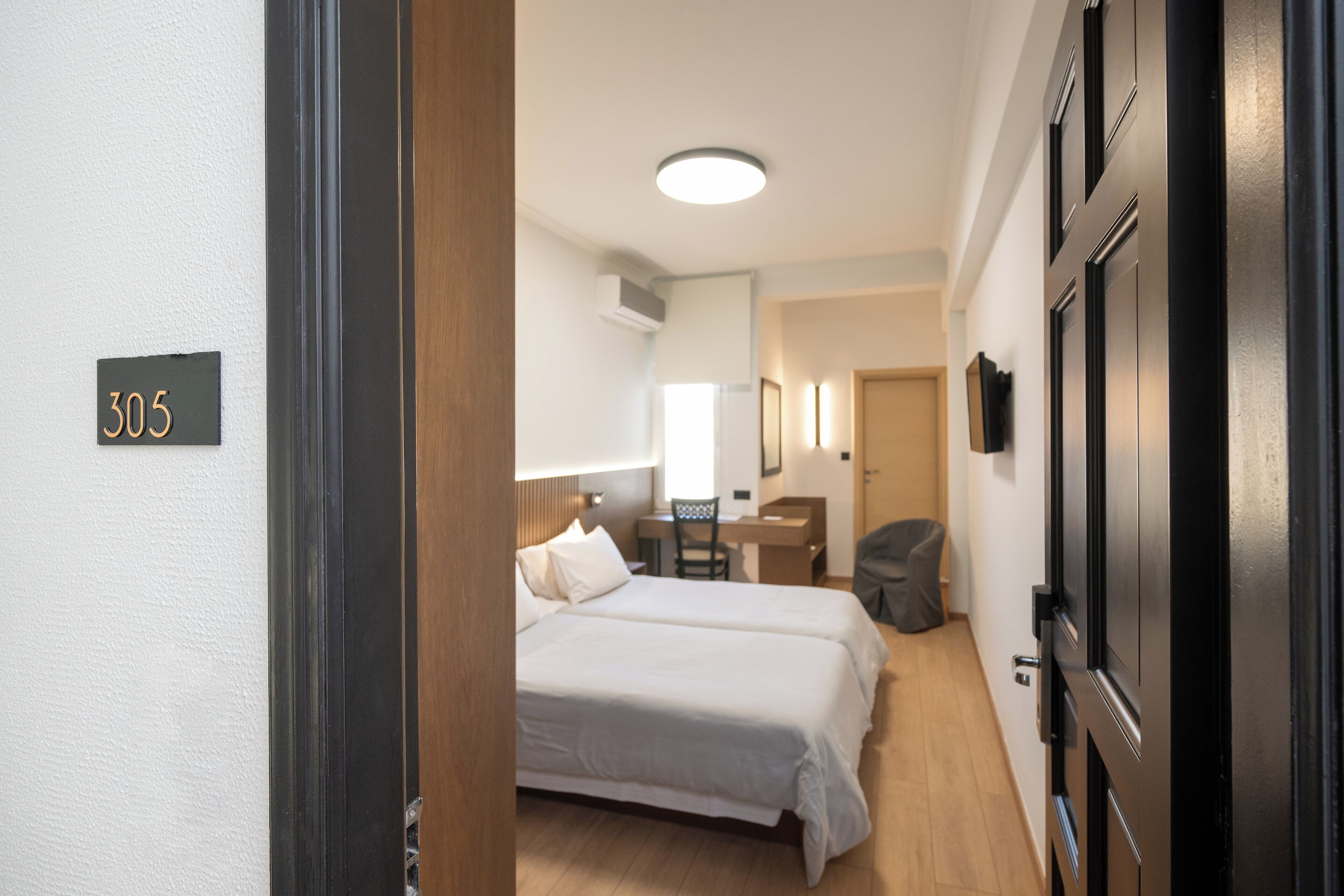 Ein Hotelzimmer mit Bett, Schreibtisch, Stuhl und einer Tür mit Hinweisschild.