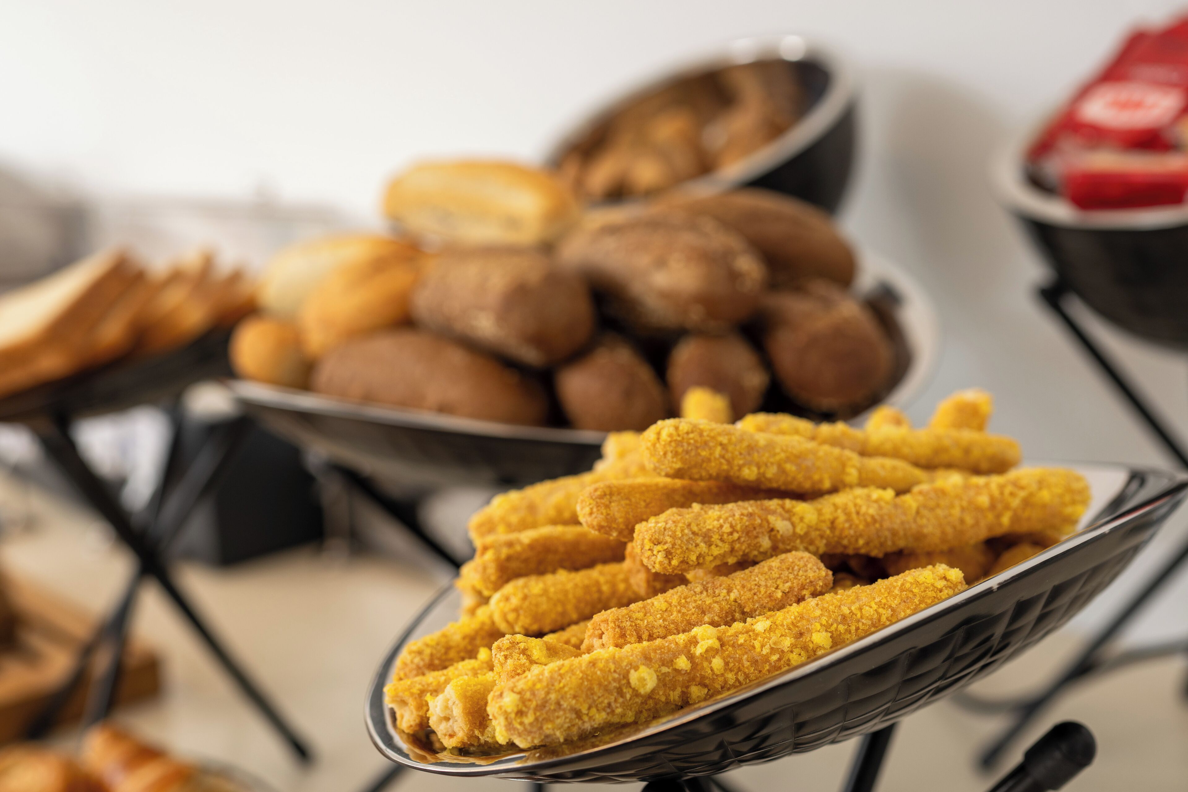A buffet with various food items including bread rolls, muffins, and breaded items.