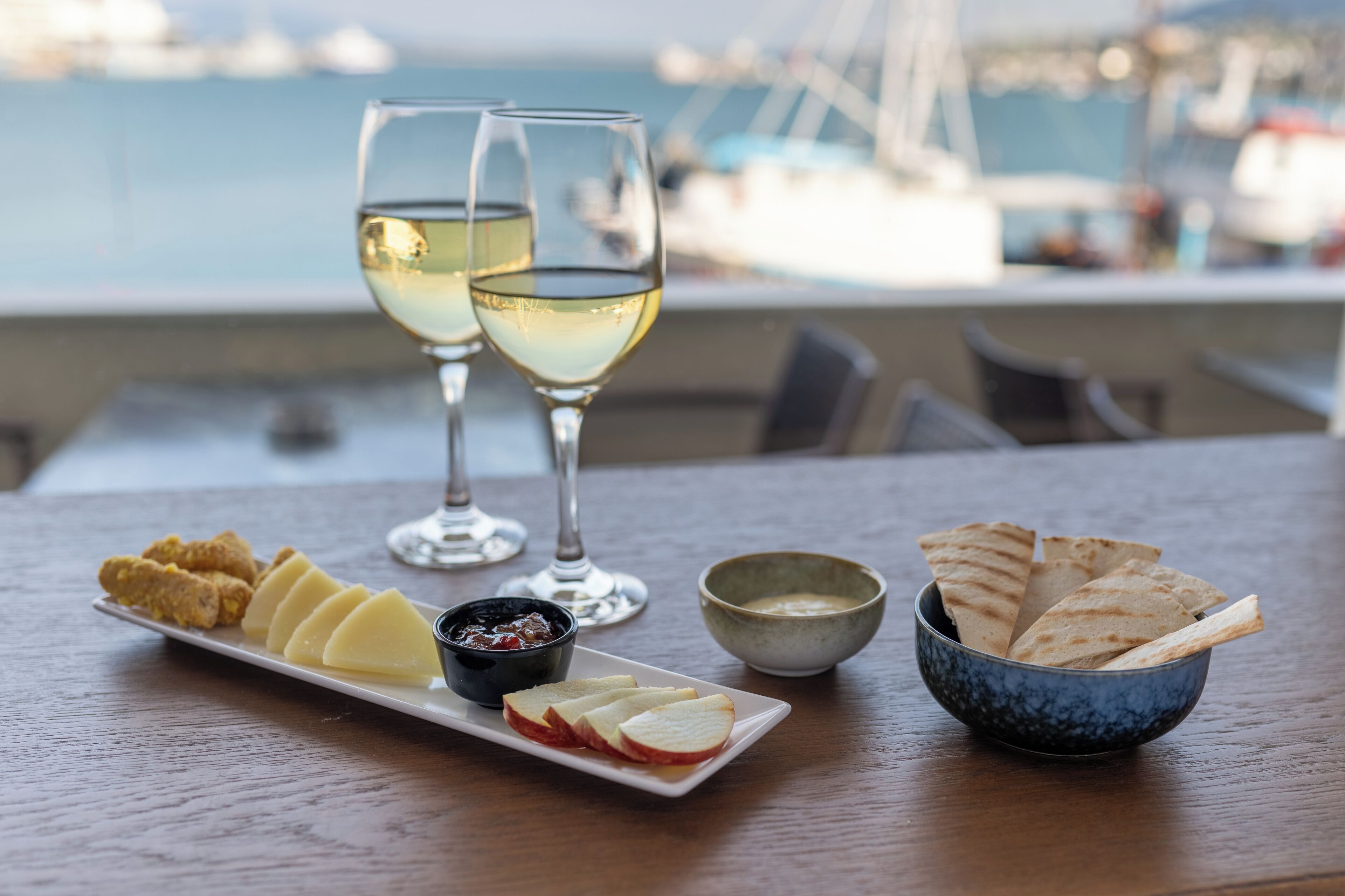 Una mesa con comida y bebidas, y una vista del puerto deportivo al fondo.