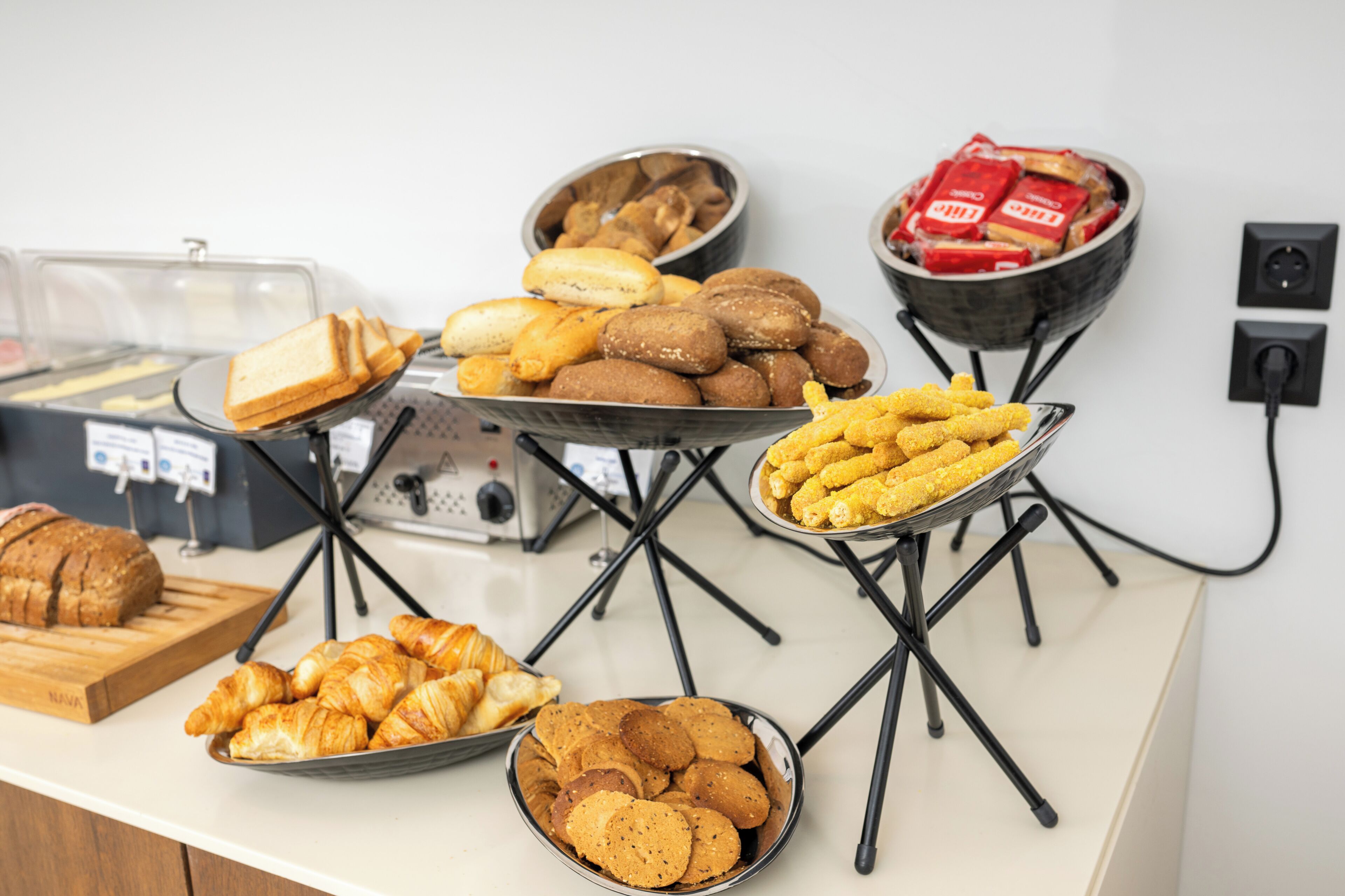 Un bufé con diversas opciones de comida, incluyendo pan, bollería y galletas.