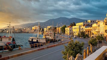 A coastal town with a marina, buildings along the waterfront, and a mountain in the background.