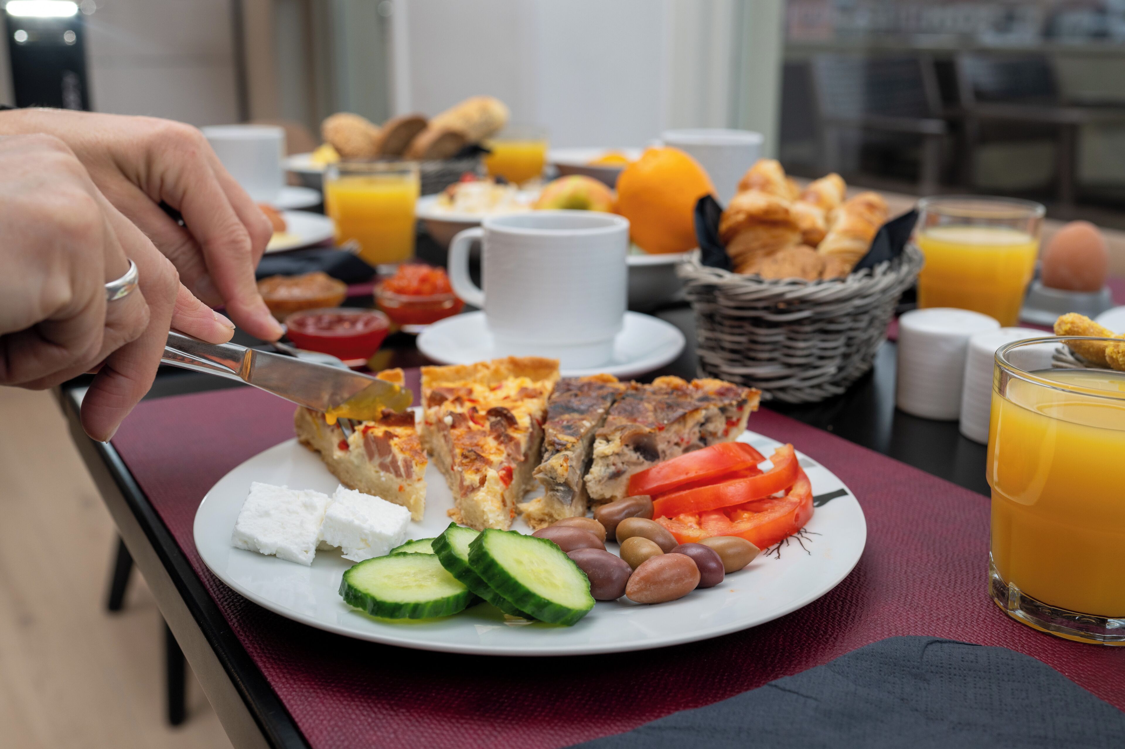 A breakfast setting with a plate of food, a glass of orange juice, and a cup.
