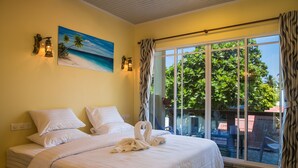 Une chambre d’hôtel avec un lit, un tableau représentant une plage et une vue sur l’extérieur.