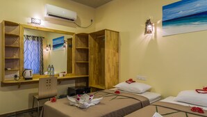 Une chambre d’hôtel avec un lit, un bureau, une chaise, un miroir et un tableau représentant une plage.