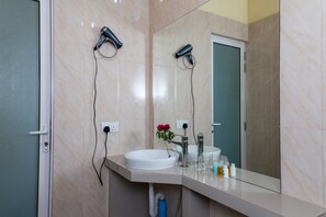 A bathroom with a white sink, a mirror, and two hair dryers mounted on the wall.