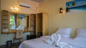 Une chambre d’hôtel comprenant un lit, un bureau, une chaise, une armoire et un tableau représentant une scène de plage.