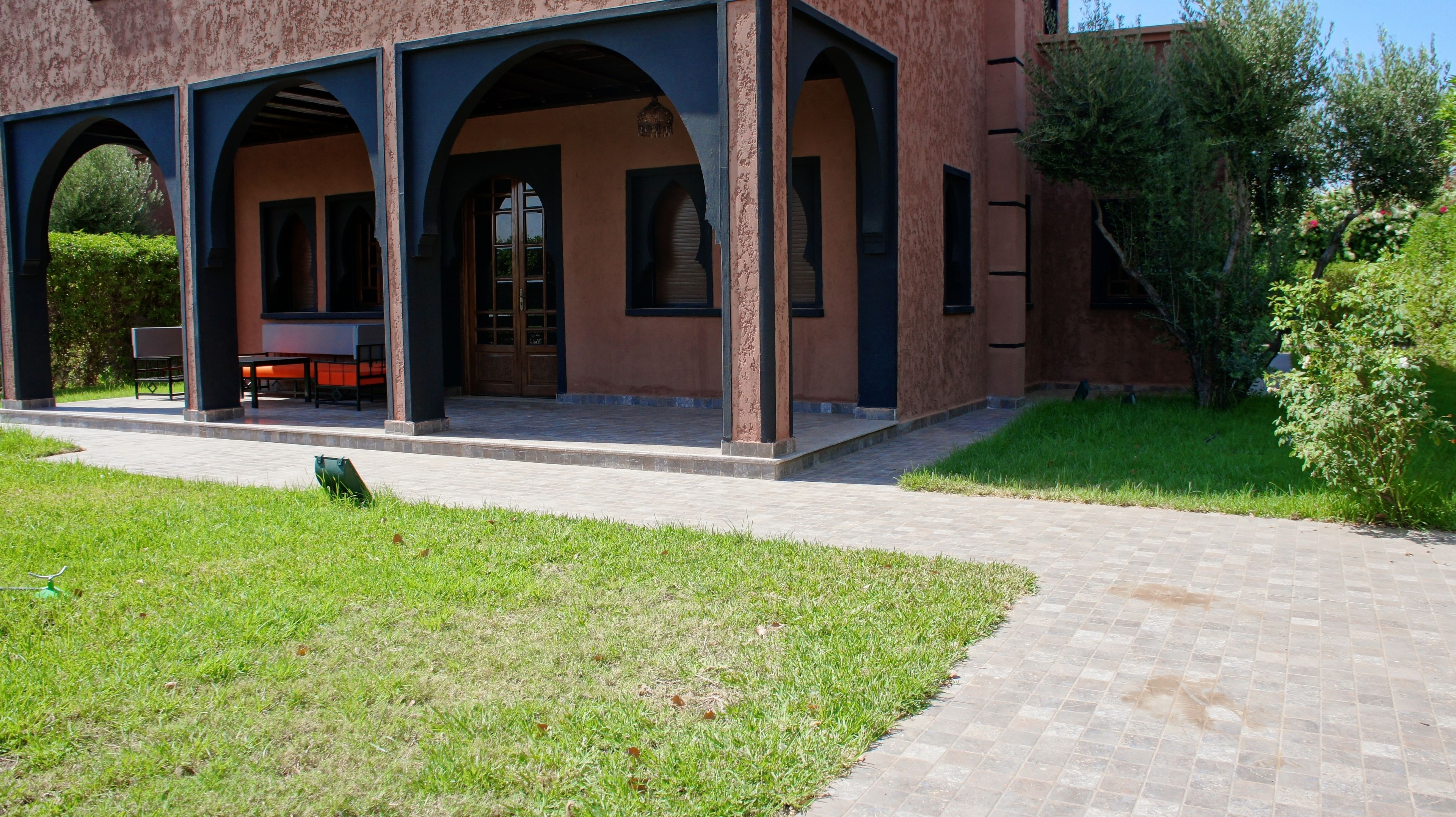A building with a covered outdoor area featuring a brick facade, arched doorways, and a paved walkway.