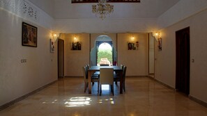 A dining area with a chandelier, a table with chairs, and artwork on the walls.