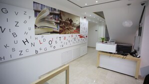 A modern reception area with a white desk, a computer, and a potted plant. - HOTEL LIBRIS boutique (Sarajevo)