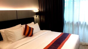 A hotel room with a large bed, a headboard, a nightstand, and a window with curtains. - Studio Ekamai (Bangkok)