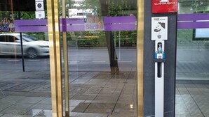 A hotel entrance with a glass door, a purple barrier, and a parking meter. - Studio Ekamai (Bangkok)