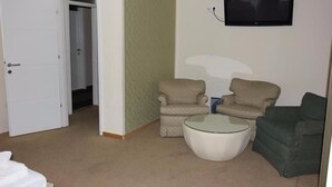 A room with two armchairs, a round coffee table, and a television mounted on the wall. - ETN Hotel (Sarajevo)
