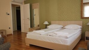 A neatly made bed with white linens and pillows, a bedside lamp, and a wooden headboard. - ETN Hotel (Sarajevo)