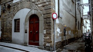 A stone building with a red door and a no parking sign. - Borgo San Jacopo Deluxe (Florence)