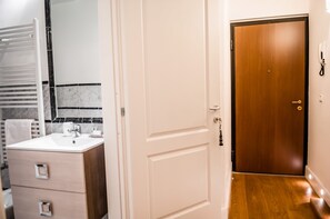 A modern bathroom with a white sink, wooden cabinet, and a mirror.