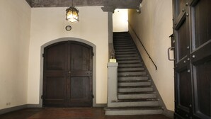 A staircase with a wooden handrail and a dark wooden door at the bottom. - Borgo San Jacopo Deluxe (Florence)