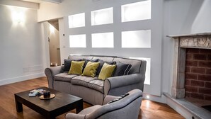 A modern living room with a grey sofa, a wooden coffee table, and a fireplace. - Borgo San Jacopo Deluxe (Florence)