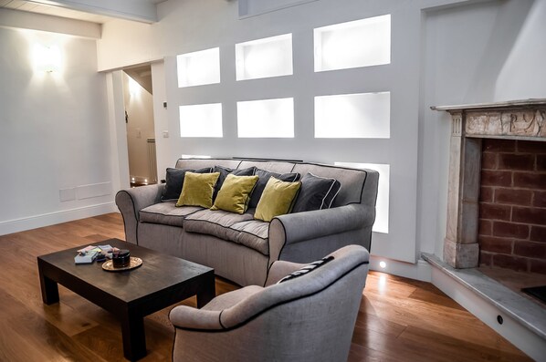 A modern living room with a grey sofa, a wooden coffee table, and a fireplace.