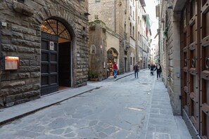 A narrow stone-paved street with historic buildings, a large wooden door, and a sign indicating no parking.