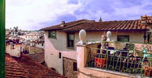A residential building with a tiled roof, a balcony with a metal railing, and a view of neighboring buildings.