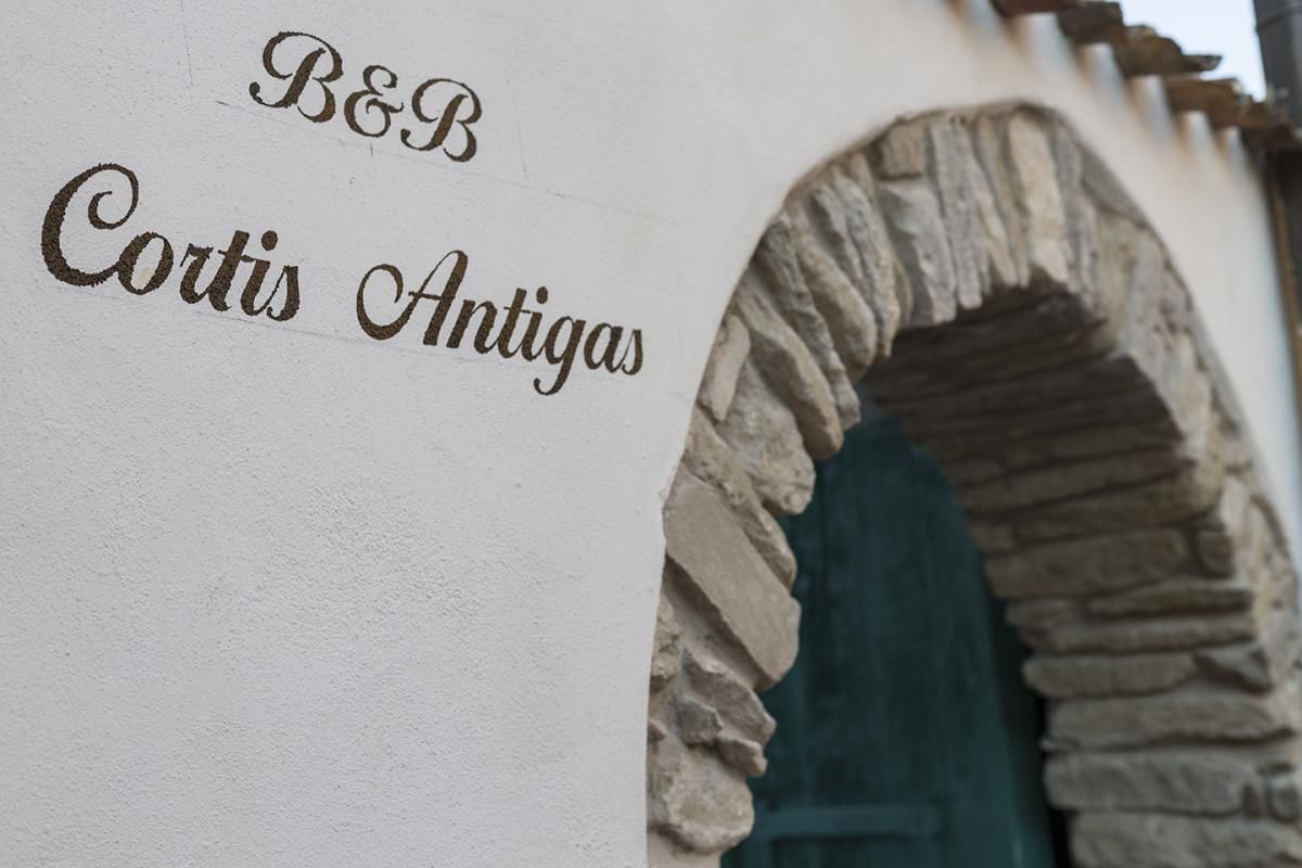 En stenvalvbåge med en skylt som visar texten "B&B Cortis Antigas".