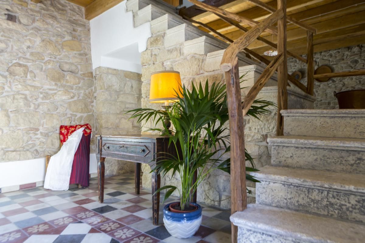 A stone staircase with a wooden railing, a potted plant, and a table with a lamp.