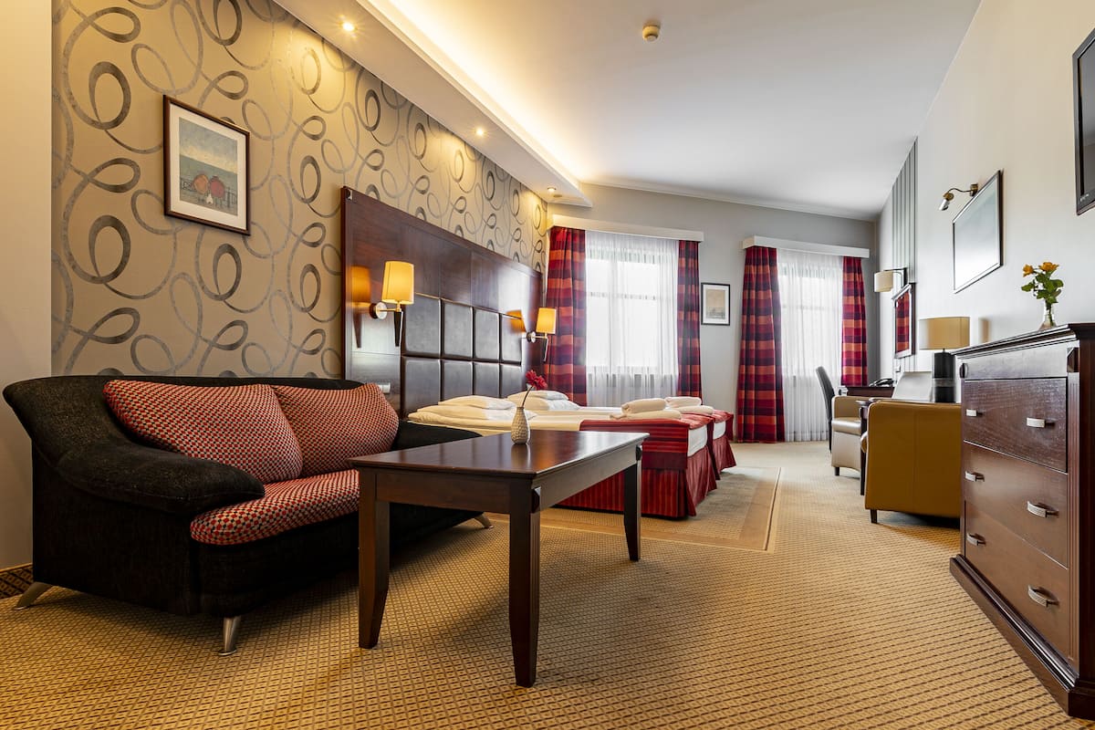 Een hotelkamer met een bank, een bed, een bureau en een dressoir.