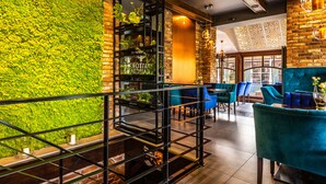 A restaurant with a green wall, blue chairs, and a brick wall. - Hotel Galicja Wellness & SPA (Oswiecim)