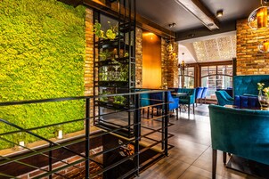 Um restaurante com parede verde, cadeiras azuis e parede de tijolos.
