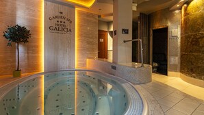 A modern spa area with a hot tub, a wooden wall with the hotel name, and a potted plant.