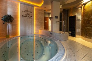 Uma área de spa moderna com hidromassagem, parede de madeira com o nome do hotel e um vaso de planta.