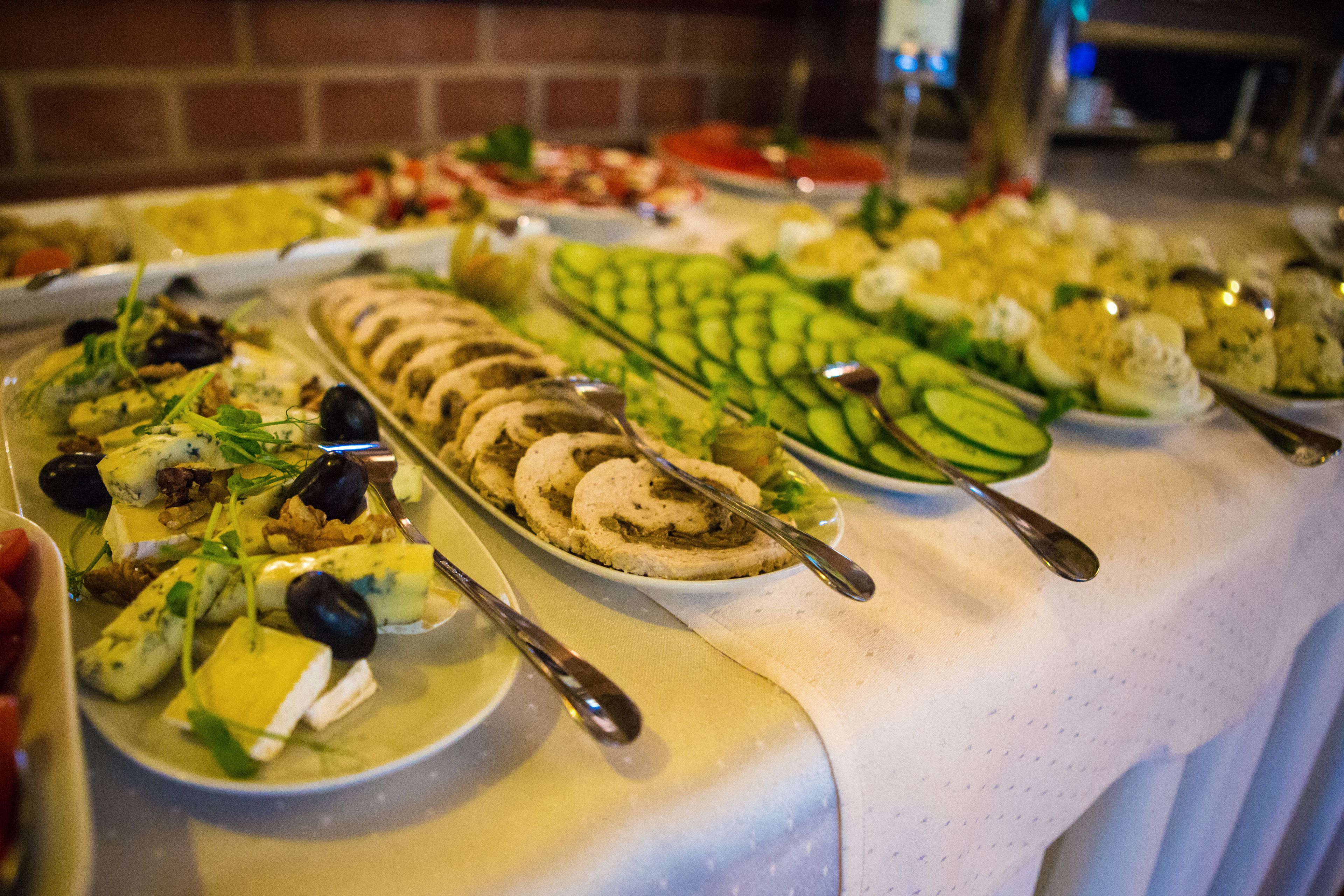Una mesa de buffet con diversos platos, incluyendo ensaladas, quesos y carnes variados.