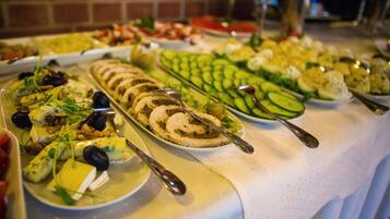 Una mesa de buffet con diversos platos, incluyendo ensaladas, quesos y carnes variados.