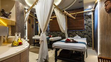Un cuarto de spa con una cama grande, una camilla de masaje y un tocador con lavabo y botellas.
